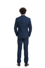 rear view of elegant man in navy blue suit holding hands in pockets
