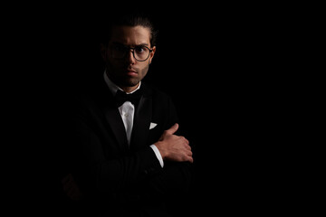 Obraz premium mysterious elegant man in black tuxedo folding arms