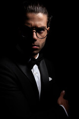 elegant young groom with glasses posing in a mysterious light