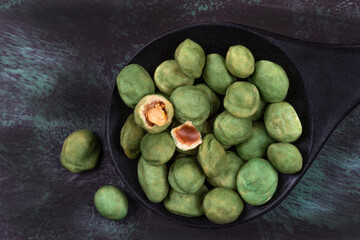 Pile of wasabi coated peanuts isolated on wooden dark grey background