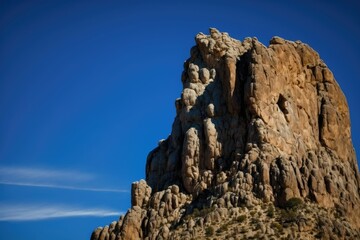 Majestic and imposing cliff face, rising tall and proud against a clear blue sky generative ai