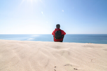 Mature man, over fifty years old. Meditating on the sand dunes. The dunes, the sea, the blue sky...