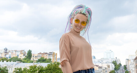 Portrait of a woman in yellow glasses and with a dreadlocks hairstyle.
