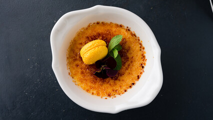 Dessert creme brulee garnished with macaroons and mint.