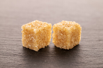 Two brown sugar cubes, close-up, on a slate board.