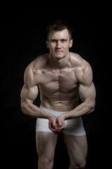 Fototapeta na wymiar Handsome muscular guy in underwear. The photo was taken in a studio on a dark background.