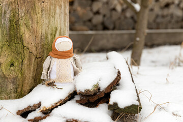 winter holidays. doll in national costume with a bundle of firewood in the snow