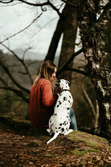 Frau sitzt mit Dalmatiner im Wald