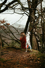 Dalmatiner schaut über Schulter von Frau in Wald