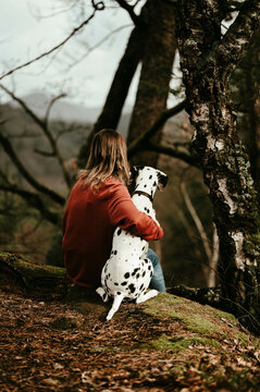 Frau sitzt mit Dalmatiner im Wald