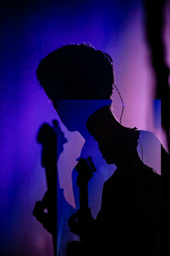 Silhouette of a guitarist under blue stage lights during a concert, capturing the intense atmosphere of a rock performance.