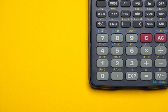Calculator for math, physics, engineering or business homework and tax and finance calculations on a yellow background. Cool minimal flat lay, copy space.