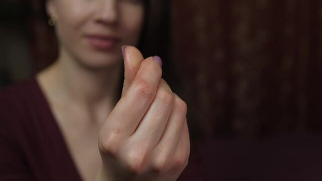 Close-up of a woman's hand showing a gesture asking for money on a black background. Portrait of mercantile woman demanding money for purchases. The girl demands money. slow motion