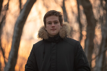 Young smile man in winter forest at sunset
