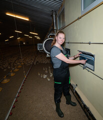 Junge Landwirtin kontrolliert die Lüftungs- Heizanlage in einen Geflügelmastbetriebe. - obrazy, fototapety, plakaty