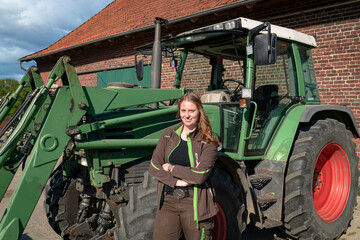 Jungbäuerin steht an ihrem Trecker, auf einen Hof. © Countrypixel