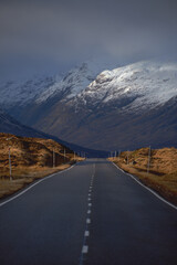 A road leading through the Scottish Highlands of Glen Coe to the snow-capped mountains. Scotland