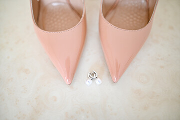 Fototapeta premium The bride earrings in white gold with diamonds lie on table next to shoes.