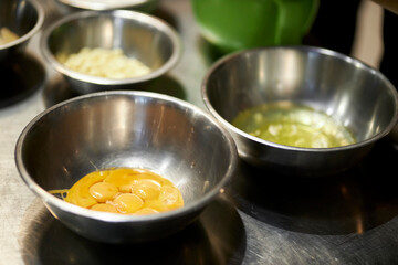 Chicken yolks in a metal bowl. Close-up of egg yolks inside a metal bowl. Fresh organic eggs fall into a bowl. Preparing ingredients for baking.