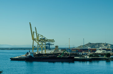 Fototapeta na wymiar Cranes of the port of Ferrol and a ship loading wood