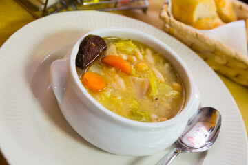 Thick Catalan soup escudella with mix of vegetables, meat and traditional black sausage butifarra..