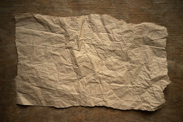 Obraz premium A piece of crumpled yellow paper on a wooden table.Photo of a vintage crumpled sheet for packaging.