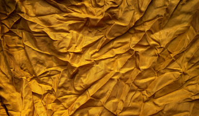 Photo of the texture of the golden fabric. Golden textile background.Crumpled yellow background.