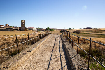 bridge over Sequillo river - dirt road on a summer landscape approaching Tamariz de Campos,...