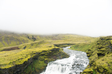 Fototapeta na wymiar Waterfall in the beautiful landscape in Icelandic environment during cloudy, misty day