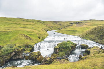 Fototapeta premium Waterfall in the beautiful landscape in Icelandic environment during cloudy, misty day