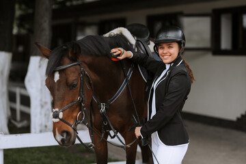 Girl taking care of her horse before horse riding. Equestrian sport.