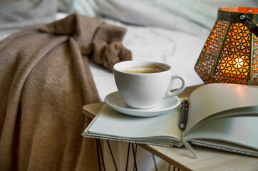 Home coffee time, coffee cup with notebook and table lamp