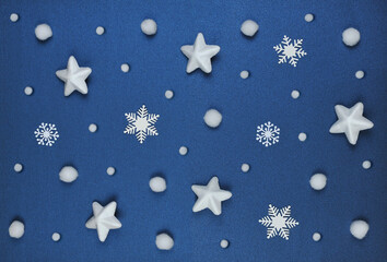 White snowballs, stars and snowflakes of various shapes and sizes isolated on a dark blue- pearl background. Top view, flat lay