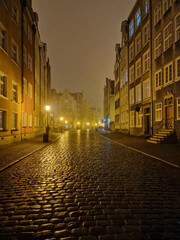 View of a fragment of a street and tenement houses, characteristic of the old town of Gdansk on a foggy winter night, Gdansk, Poland.