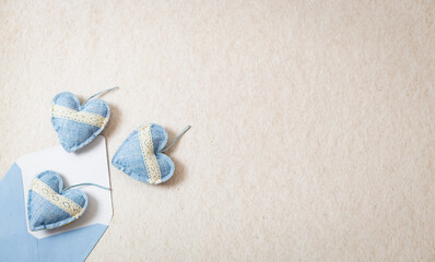 Envelope with three textile hearts spilling out on a stone background.