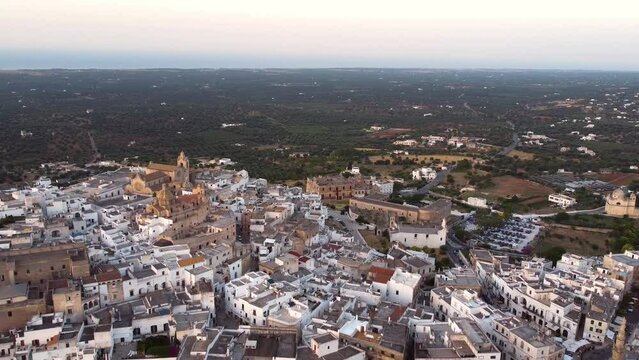Aerial drone footage of Ostuni - La Citta Bianca (white city), Puglia, Italy at sunset. Reveal scene of Cathedral, main square, the medieval historic old town landmark tourist destination from above.