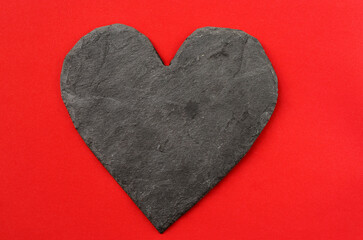 Fototapeta na wymiar dark stone heart on red background