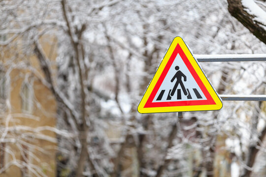 Snow on a road sign warning of pedestrians. Winter background, selective focus