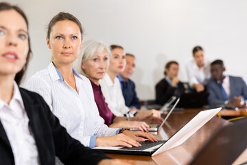 Fototapeta premium Young businesswoman attending conference in meeting room in company office and using laptop.