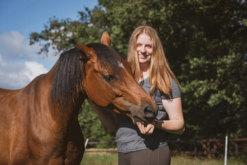 Ein Pferd frisst einer jungen Frau, Leckerlies aus der Hand.
