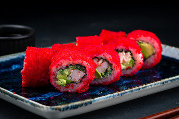 Set of sushi rolls with shrimp, avocado, cucumber, rice, nori in red flying fish caviar.