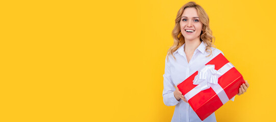 positive woman with big present box on yellow background. Woman isolated face portrait, banner with mock up copy space.