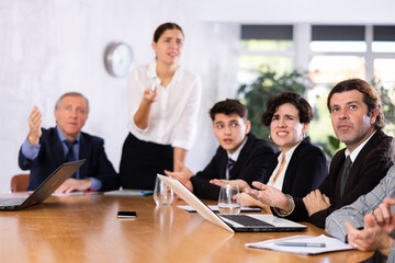Portrait of surprised adult man sitting at table in office during work meeting, looking at slide presentation