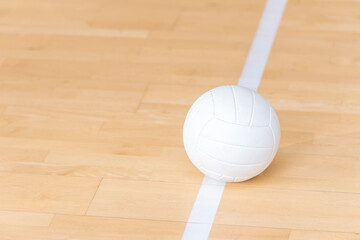 Volleyball ball on hardwood court floor with white line. Team sport. Workout online concept