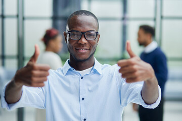 Businessman in glasses showing thumb up while looking at camera