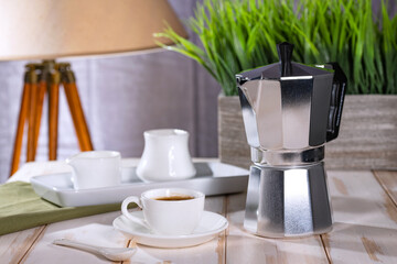 geyser coffee maker and freshly brewed coffee stand on a white kitchen table.