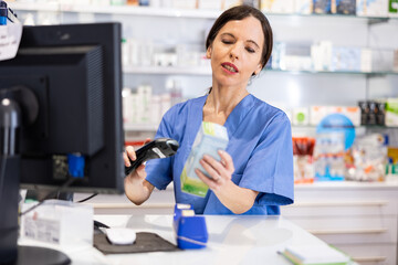 Woman druggist using barcode scanner to sell medicine in drugstore.