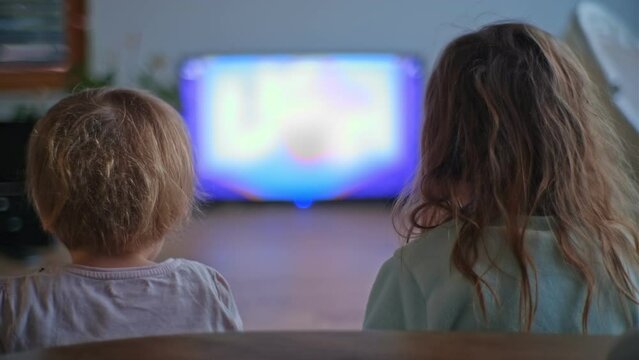 Two Young Kids Sisters Playing Together Cooperative Video Game on Gaming Console and TV