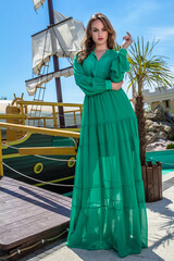 Girl in a green dress is standing by the ship
