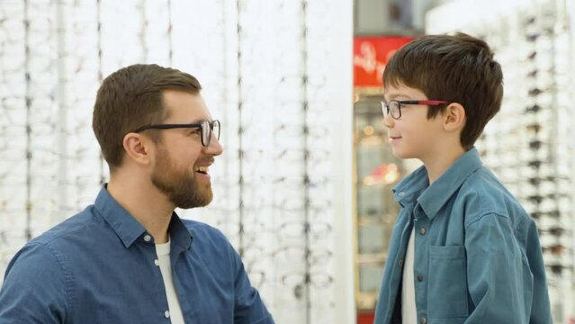 Little boy in new glasses with his father at optics store. Ophthalmology concept